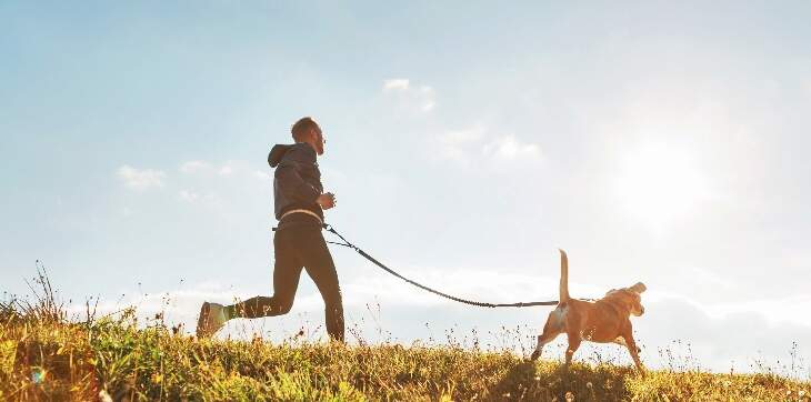 Person running with dog on grass